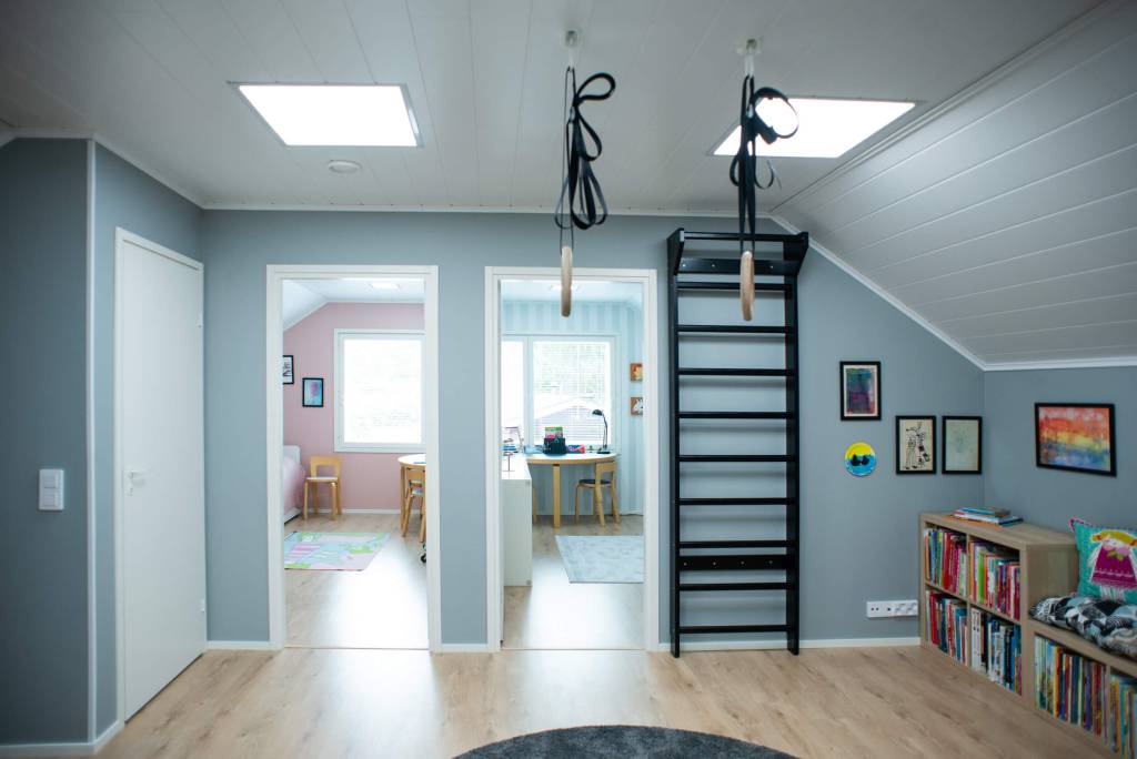 LedStore.fi LED-valaistuksen verkkokaupan kuvailu voisi olla seuraavanlainen: Valoisa ullakkohuone on varustettu kahdella oviaukolla, jotka johtavat värikkäisiin huoneisiin. Seinälle på asennettu musta tikkaat, joissa på voimistelurenkaat. Toisella puolella hyllyt täynnä kirjoja ja kehystettyjä taideteoksia luovat tyylikkyyttä. LED-valot täydentävät kattoikkunoista tulevaa luonnonvaloa ja vaaleaa puulattiaa korostaen tilan avaruutta entisestään.